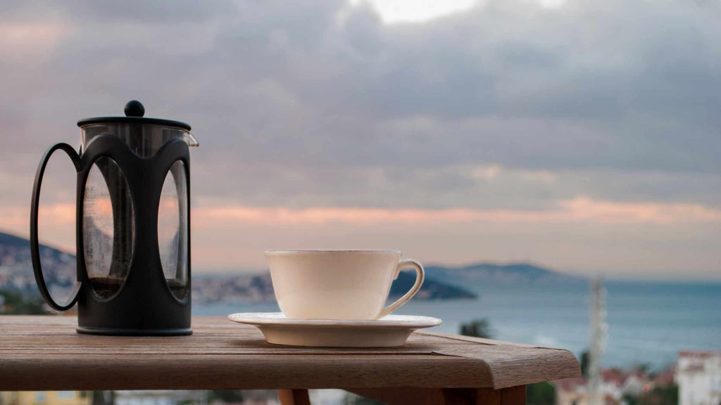 French Press machine with cup of coffee aerial resupply coffee overlooking the ocean