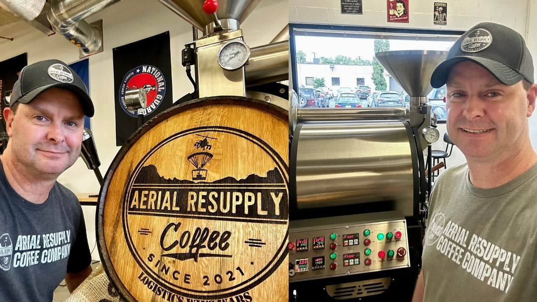two people standing next to a coffee roaster and a wooden sign