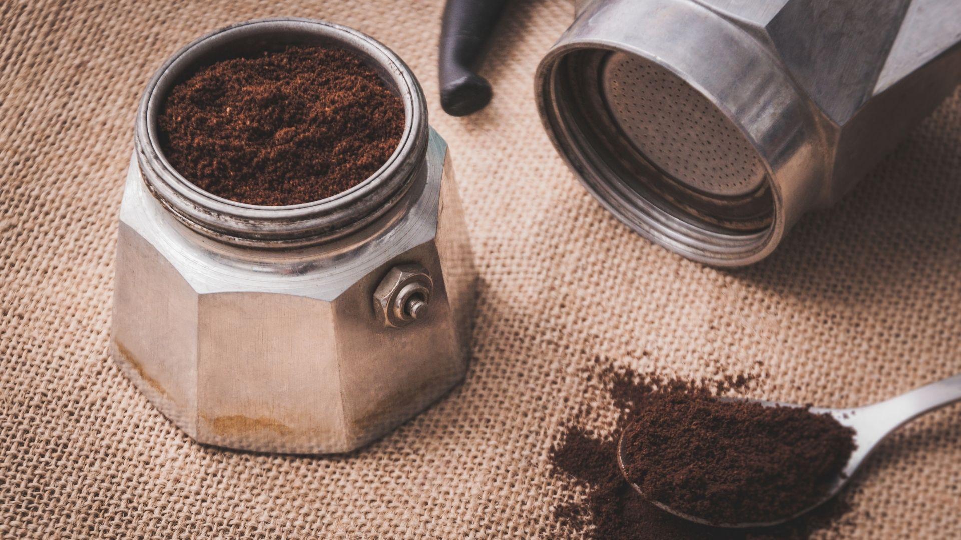 ground coffee  on a spoon and tin on a counter