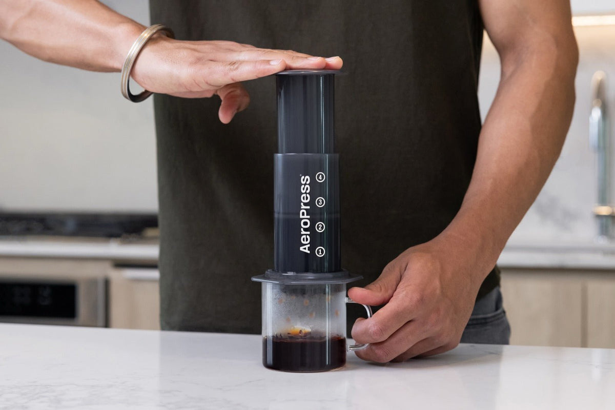 Pressing an AeroPress Original coffee maker on a kitchen counter