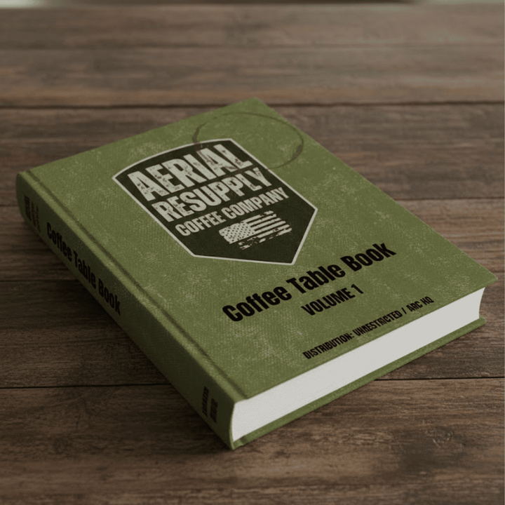 Green book titled 'Coffee Table Book Volume 1' by Aerial Resupply Coffee Company on a wooden surface