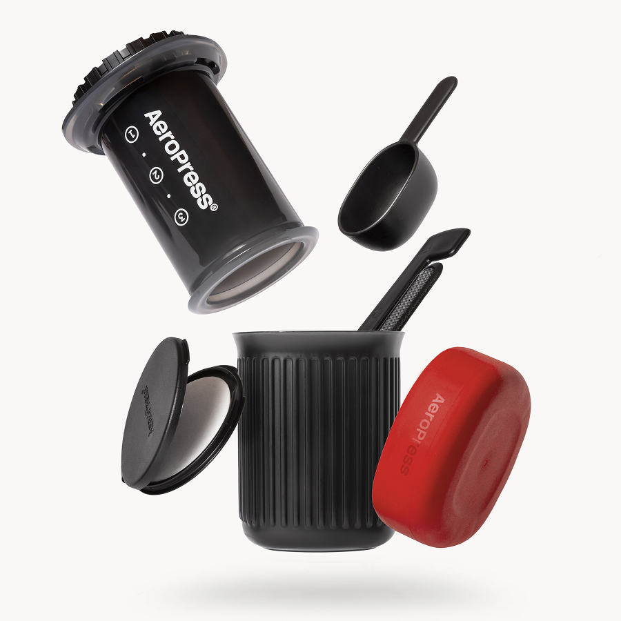Everything included with the AeroPress Go: press, 15 oz mug, red lid, filter cap, scoop and stirrer