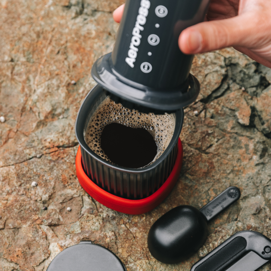Pressing a fresh cup of coffee with the AeroPress Go on a rock outdoors