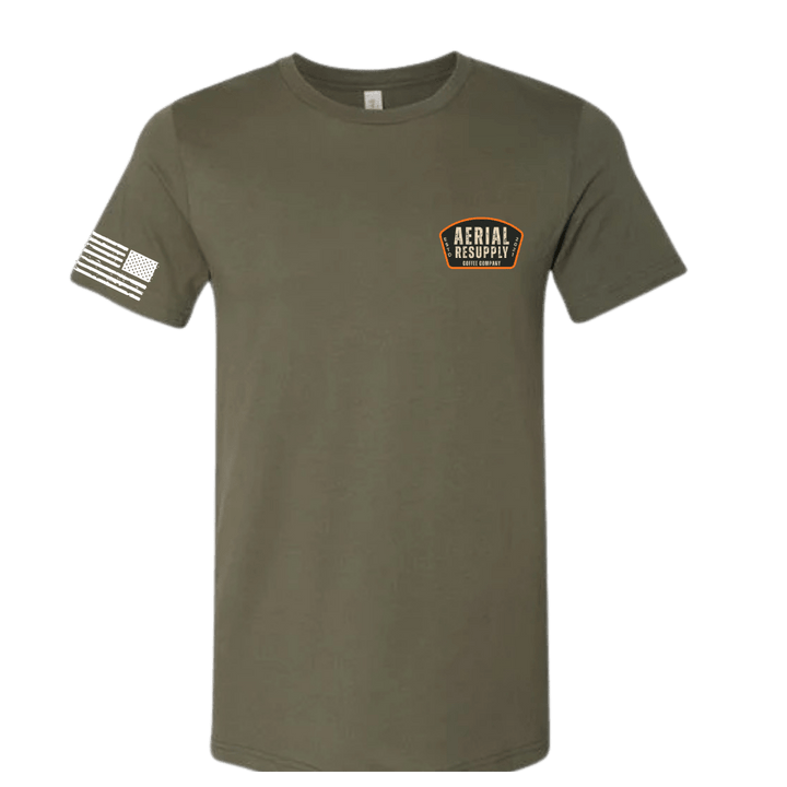 Olive green t-shirt with a logo on the chest and a flag on the sleeve against a white background
