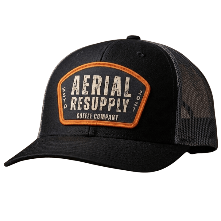 Black trucker cap with 'Aerial Resupply Coffee Company' patch on a white background