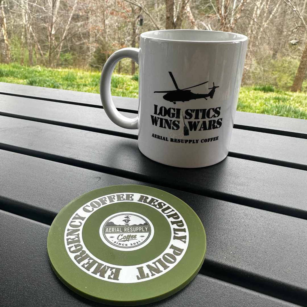 A logistics wins wars coffee mug and an Aerial Resupply Coffee emergency resupply coaster sitting on a table